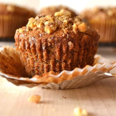 Freshly baked Banana Nut Muffins with walnuts on a rustic wooden table.