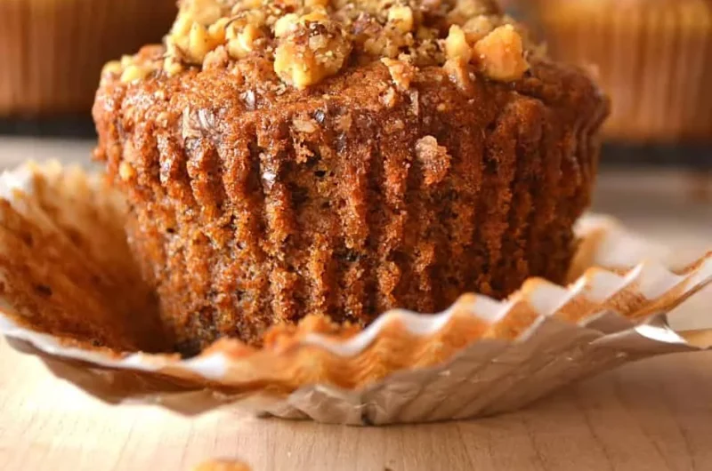 Freshly baked Banana Nut Muffins with walnuts on a rustic wooden table.
