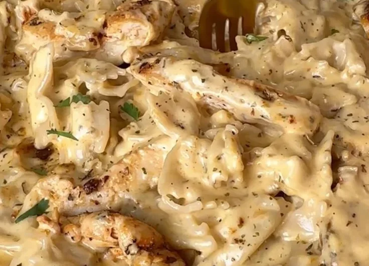 Bowl of dairy-free Chicken Alfredo topped with parsley and chicken slices.