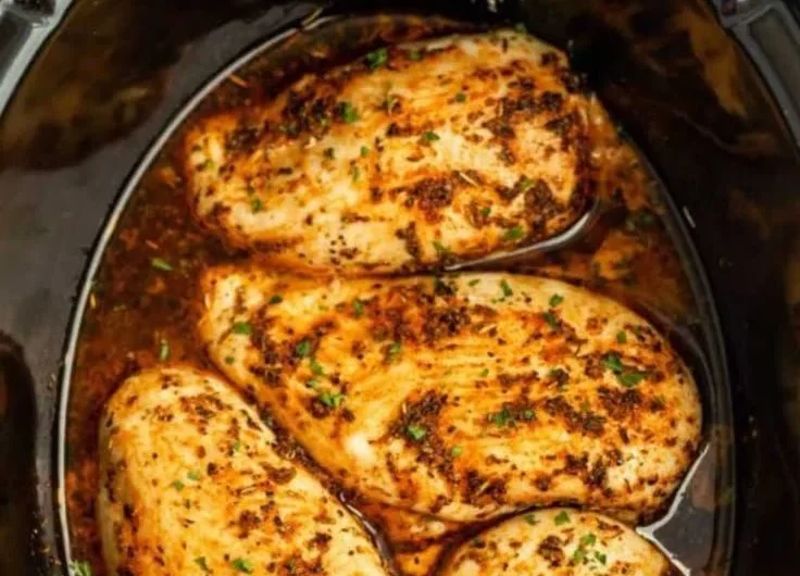 Tender slow cooker chicken breasts served with vegetables and herbs.
