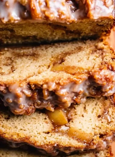 Amish apple fritter bread with apple chunks and glaze on a wooden table