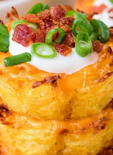 Plate of loaded tater tots appetizers topped with cheese, bacon, and sour cream.