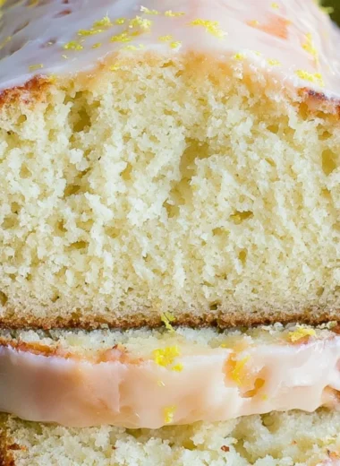 Moist lemon pound cake served on a plate, garnished with lemon slices