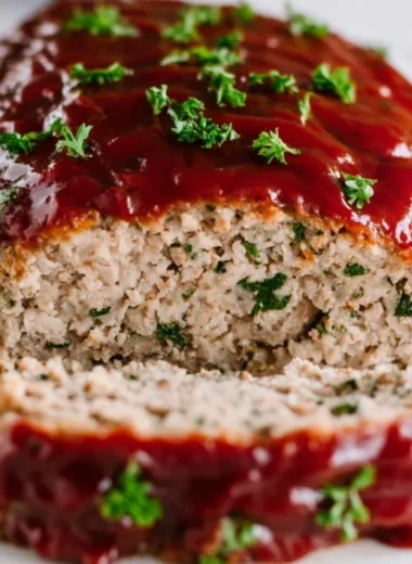 Delicious and juicy turkey meatloaf on a plate with herbs and vegetables