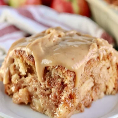 Slice of cozy Apple Dapple Cake topped with nuts and caramel drizzle.