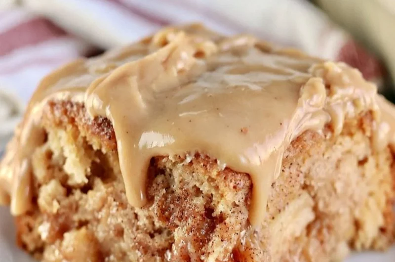 Slice of cozy Apple Dapple Cake topped with nuts and caramel drizzle.