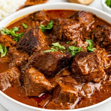 Delicious bowl of cozy Beef Vindaloo garnished with fresh herbs and spices