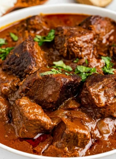 Delicious bowl of cozy Beef Vindaloo garnished with fresh herbs and spices
