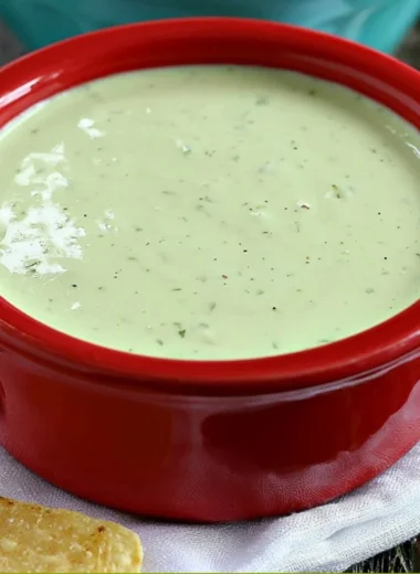 Cozy creamy jalapeño dip in a bowl garnished with herbs.
