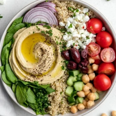 Delicious cozy Mediterranean hummus bowl topped with fresh vegetables and spices.