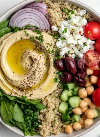 Delicious cozy Mediterranean hummus bowl topped with fresh vegetables and spices.
