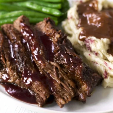 Delicious Crock Pot Chuck Roast served with vegetables and gravy.