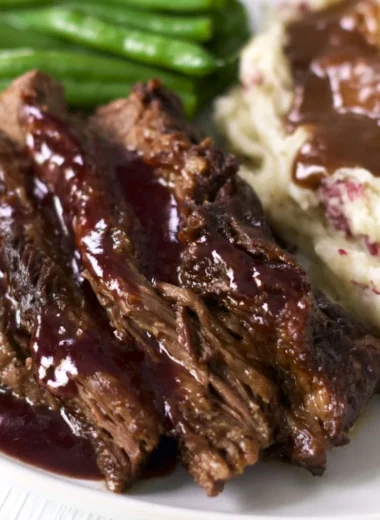 Delicious Crock Pot Chuck Roast served with vegetables and gravy.