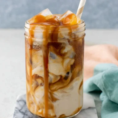 Homemade caramel iced coffee in a glass with ice and whipped cream