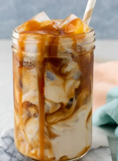 Homemade caramel iced coffee in a glass with ice and whipped cream
