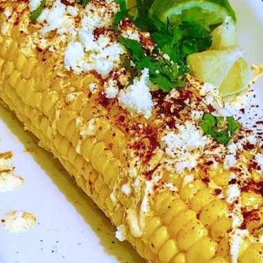 Delicious Mexican corn elotes topped with creamy sauce and cheese