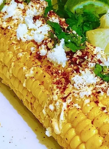 Delicious Mexican corn elotes topped with creamy sauce and cheese